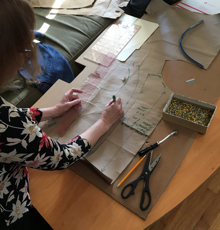 A pair of hands draft out a vest pattern onto brown paper. 